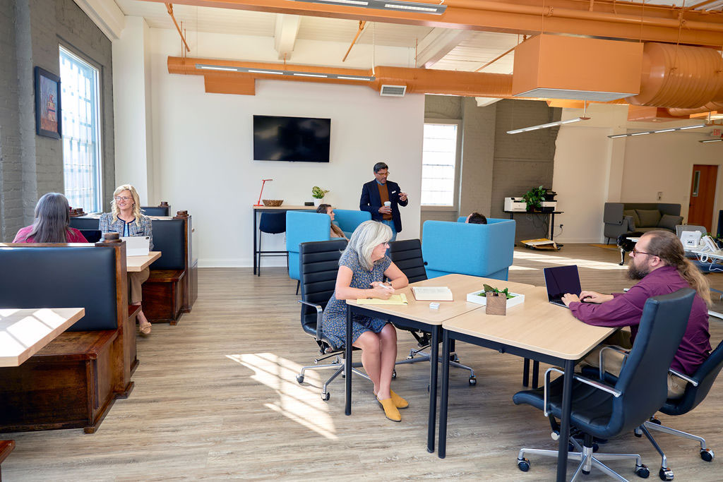 Image of several people working together at various workspaces in a coworking facility.