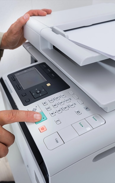 This image showcases a modern printer/copier, emphasizing the availability of printing and copying services at RingSpaces of Fredericksburg. A user operates the device, highlighting its accessibility and ease of use, essential for coworking professionals requiring reliable office equipment for their tasks.