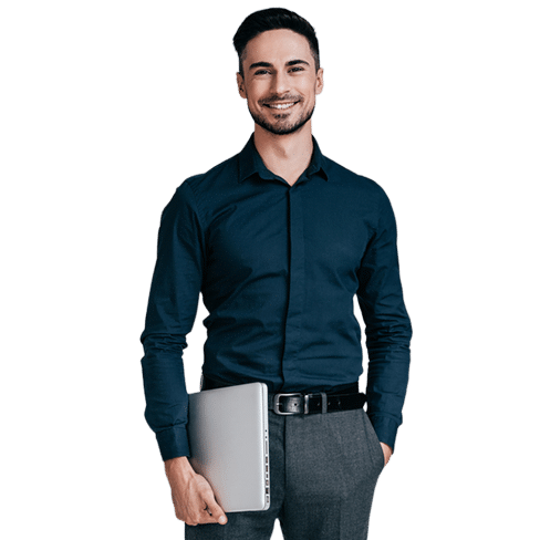 The image depicts a professionally dressed man smiling, holding a closed laptop in one hand. He is wearing a navy-blue shirt and gray trousers with a black belt. The individual conveys a confident and approachable demeanor, possibly representing a business or technology professional.